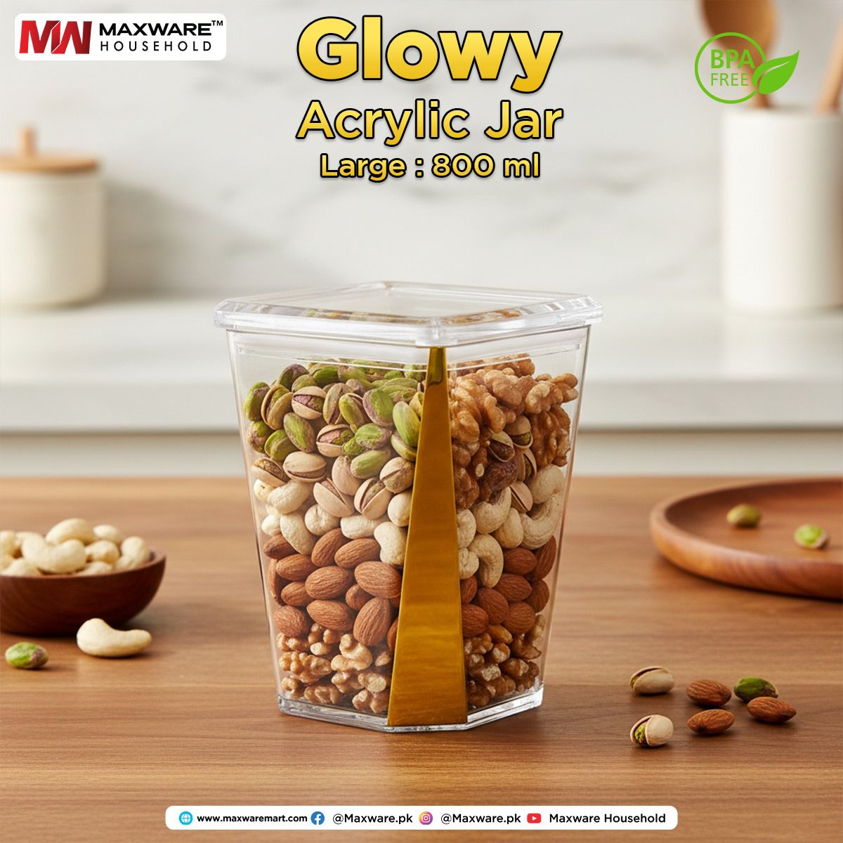 Maxware Glowy 800ml large clear acrylic airtight food storage jar with gold trim filled with layers of almonds, cashews, walnuts, and pistachios on a wooden counter.