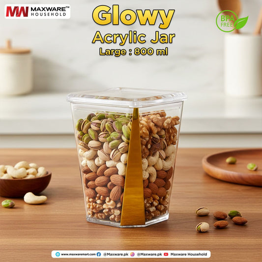 Maxware Glowy 800ml large clear acrylic airtight food storage jar with gold trim filled with layers of almonds, cashews, walnuts, and pistachios on a wooden counter.